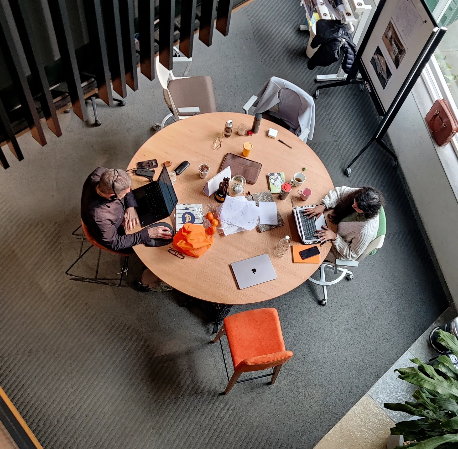 Team working at a round office table with laptops and documents